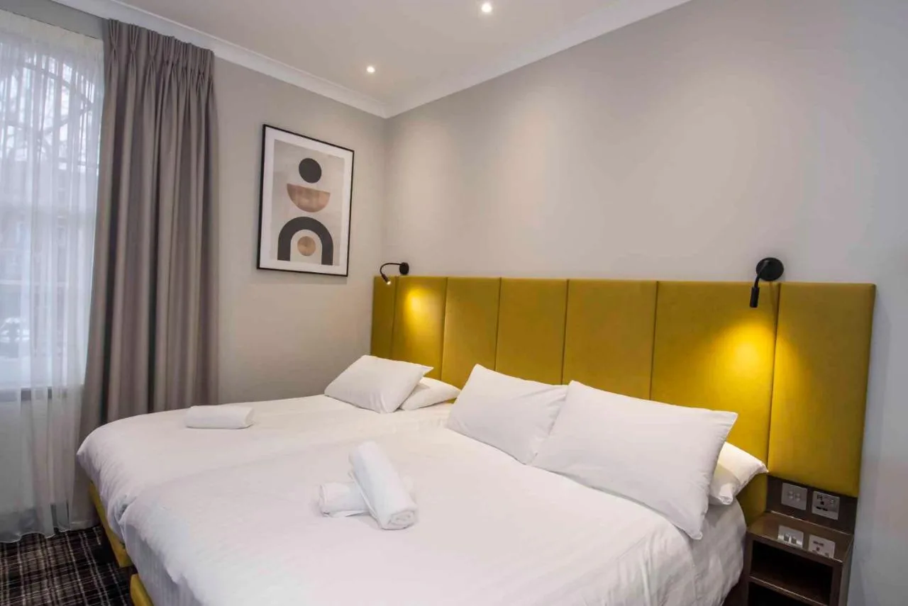 a bedroom with a large white bed with a yellow headboard at Howard Winchester Hotel in London