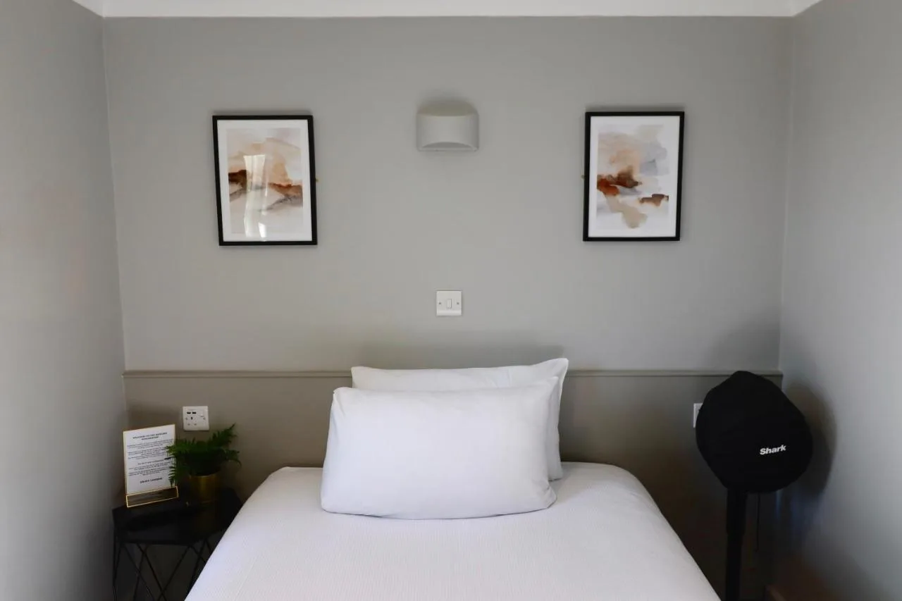 a bedroom with a white bed with two pictures on the wall at Howard Winchester Hotel in London